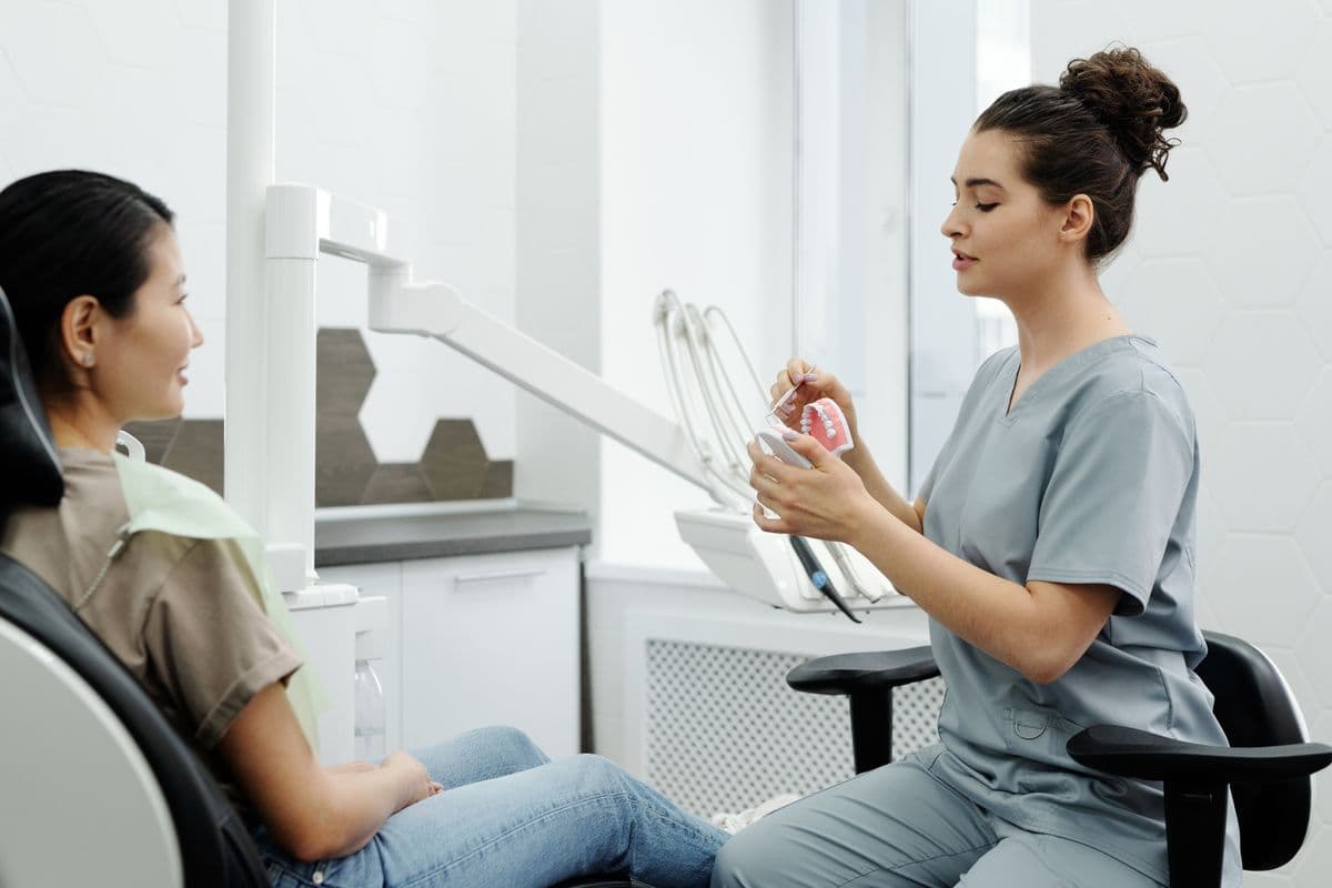 Dentist explaining a treatment plan with a tooth model to a relaxed patient in Sanpada